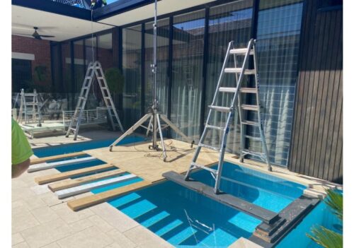 Retractable awning installation over poolside deck on modern home exterior